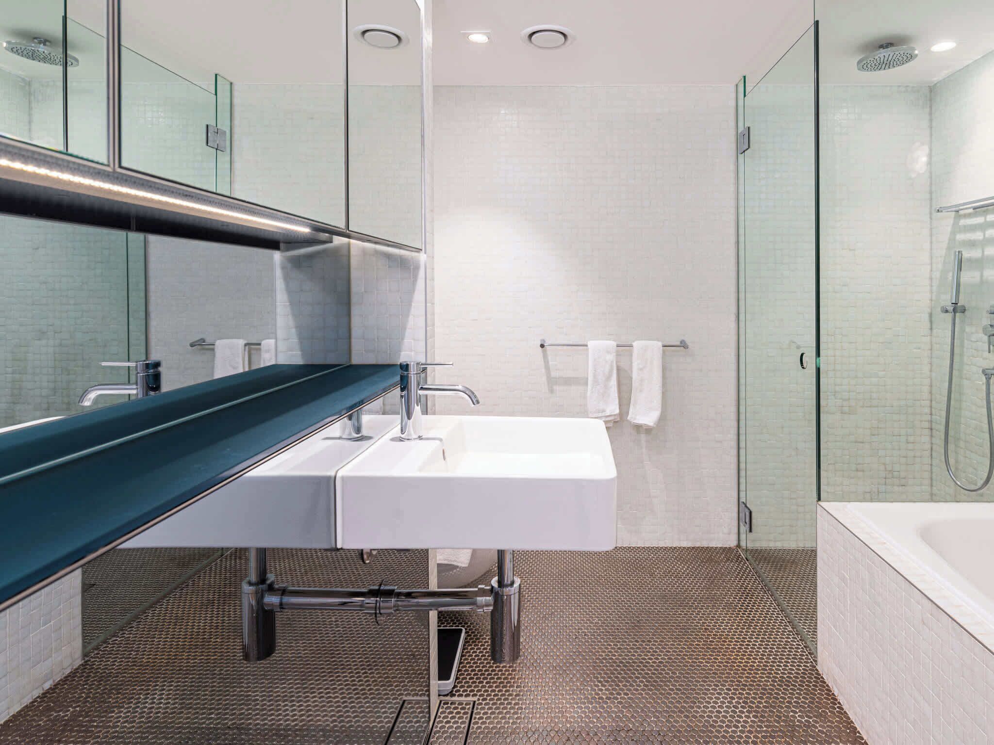 A modern bathroom with a glass shower enclosure, a white sink, and a green countertop.