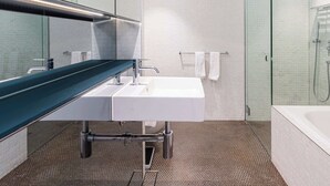 A modern bathroom with a glass shower enclosure, a white sink, and a green countertop.