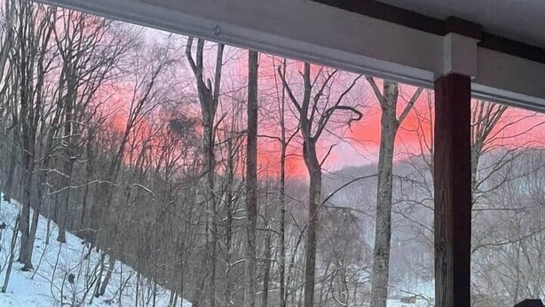 Habitació amb gran finestra que dona a un paisatge nevàs i un tramunt.