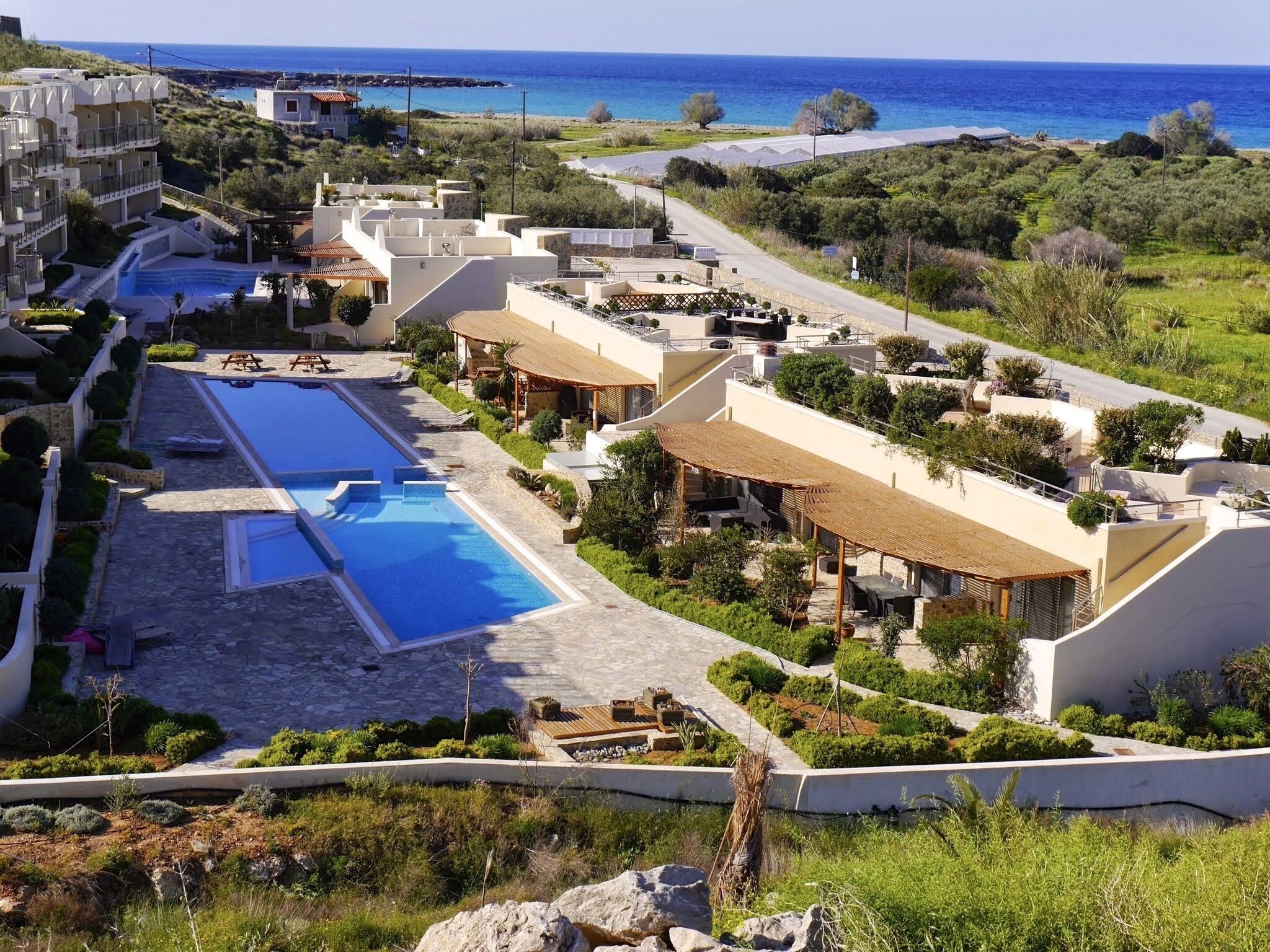 A resort with multiple swimming pools, outdoor seating areas, and a view of the sea.