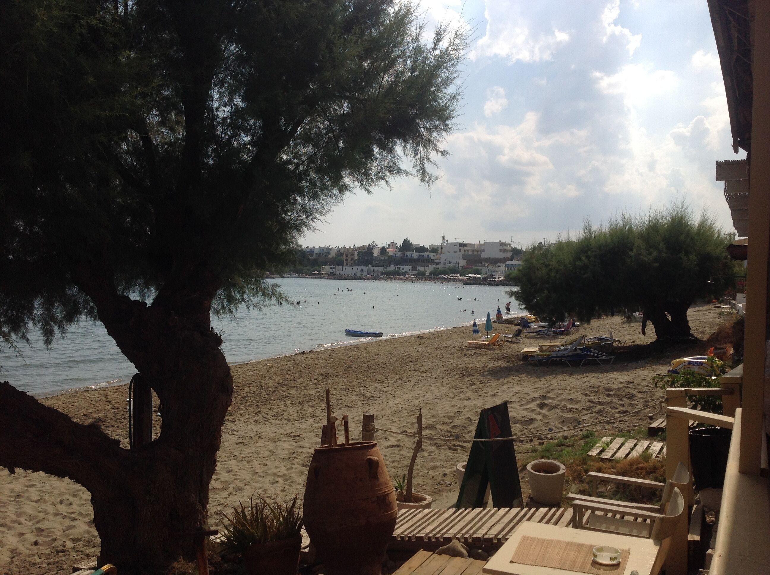 A beach with a sandy shore, a few umbrellas, and a view of a town across the water.