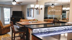 Un salon moderne avec une table à manger en bois, des canapés en cuir, un téléviseur à écran plat et un grand miroir.