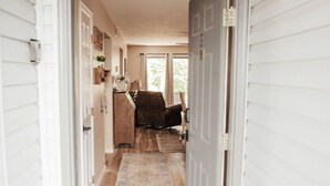 Un couloir au plancher de bois mène à une pièce dotée d’une porte.