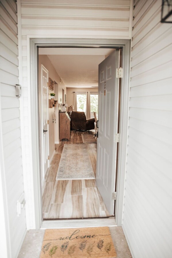 A hallway with a wooden floor leading to a room with a door.
