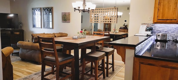 A modern kitchen with a central island, wooden cabinetry, and a dining area with a sofa and chairs.