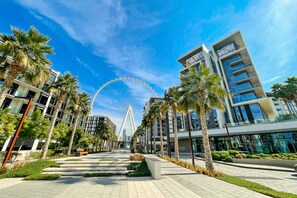 A modern urban area with a prominent Ferris wheel, palm trees, and contemporary buildings. - DHH Bluewater Island Building 2 Sea View (Dubai)