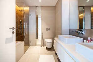 A modern bathroom with a glass shower enclosure, a white toilet, and a large vanity with a mirror. - DHH Bluewater Island Building 2 Sea View (Dubai)