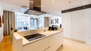 A modern kitchen with a central island, a built-in stove, and a large window providing a view of the city. - DHH Bluewater Island Building 2 Sea View (Dubai)
