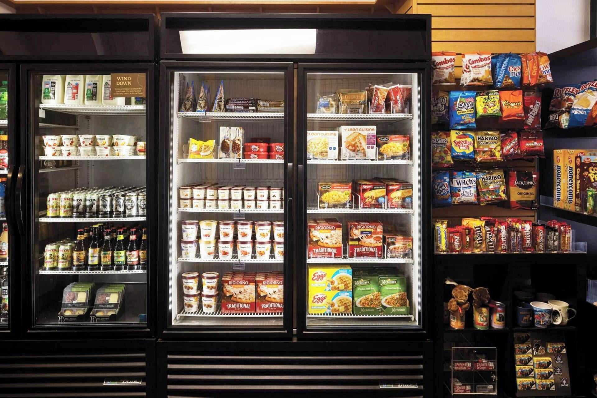 A refrigerated display case with various food items including dairy products, snacks, and condiments.