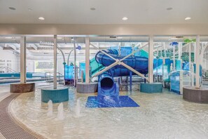 An indoor water park with multiple water slides and fountains.