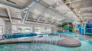 Uma piscina interior com várias pistas, um toboágua e uma área de banheira de hidromassagem.