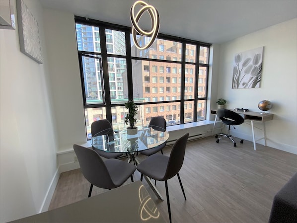 A modern office space with a large window, a round glass table, and black chairs.