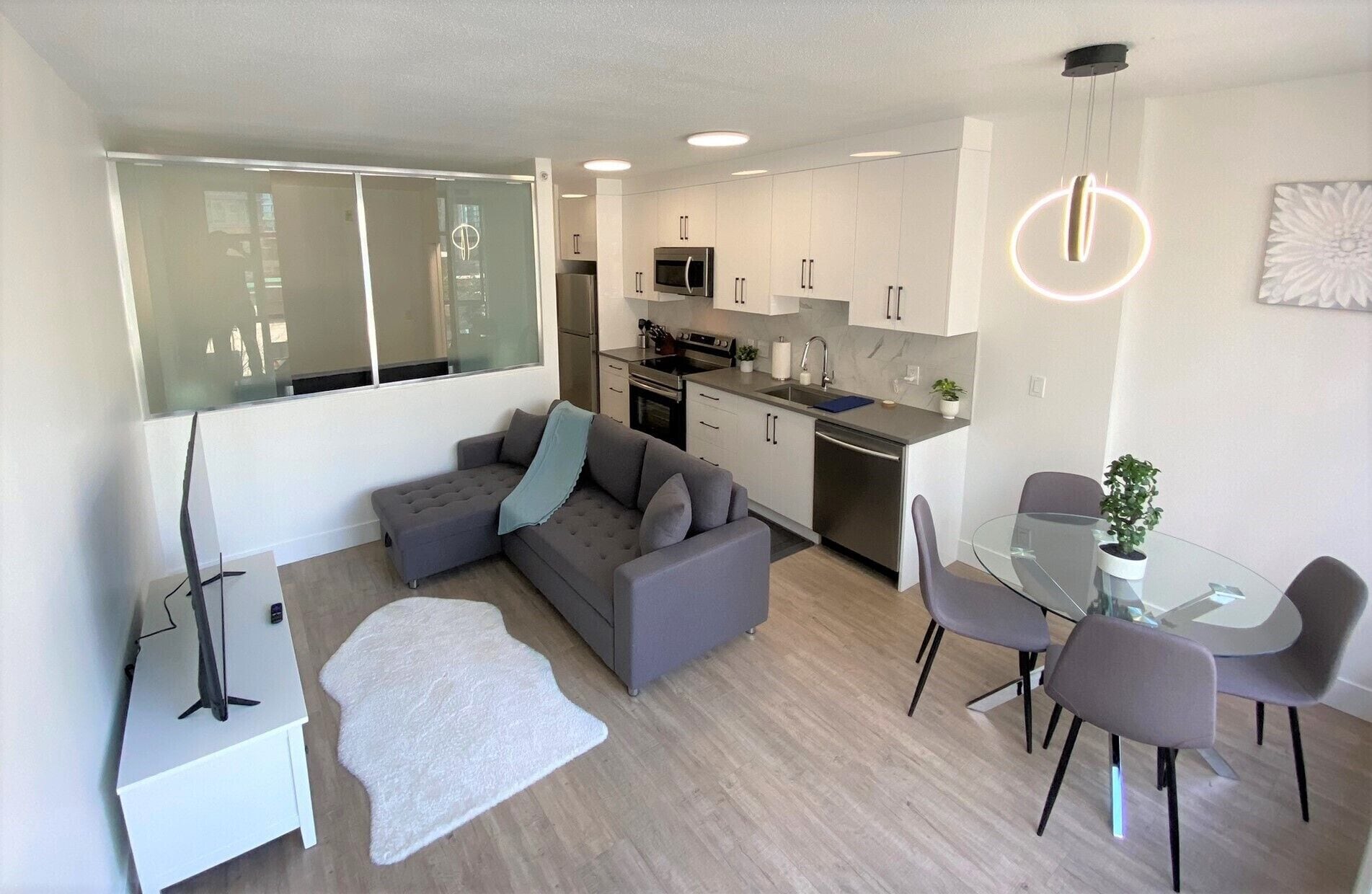 A modern apartment with a living room, dining area, and kitchen.