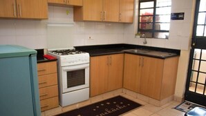 Una cocina con armarios de madera, una estufa blanca y una encimera negra.