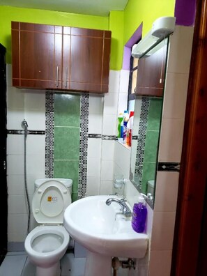 A bathroom with a toilet, sink, and wooden cabinets.