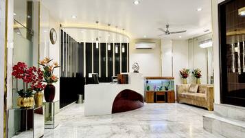 A modern reception area with a marble floor, a reception desk, a sofa, and a fish tank.