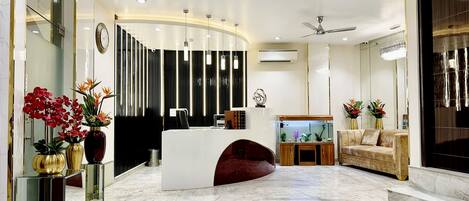 A modern reception area with a marble floor, a reception desk, a sofa, and a fish tank.