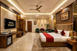 A hotel room with a bed, seating area, TV, and a minibar. - Hotel Peridot Deluxe Delhi Airport (New Delhi)