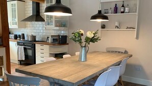 Une cuisine moderne avec un îlot central en bois, des chaises blanches et des luminaires suspendus.