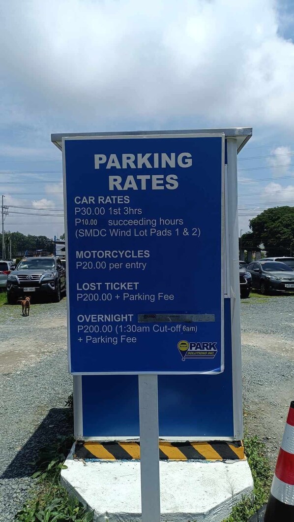 A blue parking sign with rates for cars, motorcycles, lost tickets, and overnight parking.