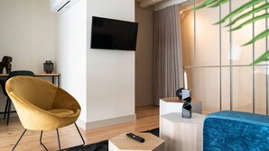Ein modernes Wohnzimmer mit einem gelben Sessel, einem blauen Sofa, einem Flachbildfernseher und einem kleinen Tisch mit einer Fernbedienung.