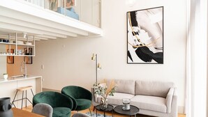 Ein modernes Wohnzimmer mit einer Couch, Sesseln, einem Couchtisch und einem Bild an der Wand.