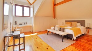 Ein Schlafzimmer mit Bett, Nachttisch und Schreibtisch mit Stuhl. Es gibt ein Fenster und einen Spiegel an der Wand.