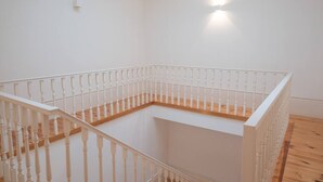 Eine Ecke eines Raumes mit weißen Wänden, Holzboden und weißer Brüstung.