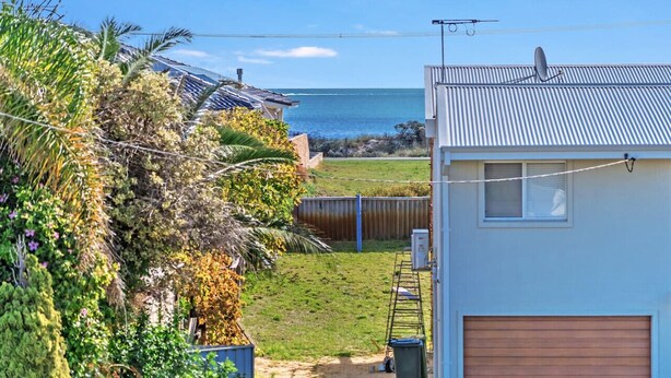 A residential property with a view of the ocean, a fenced yard, and a garage. - Giggles Beach House in Silver Sands (Silver Sands)