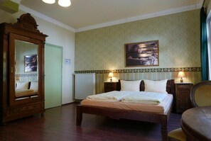 A hotel room with a large bed, a wooden dresser, a mirror, and a painting on the wall. - Hotel Löwenherz (Oppenau)