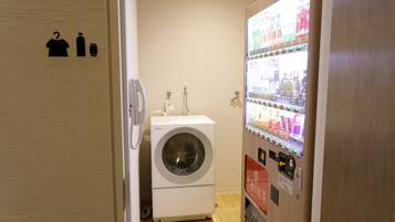 A laundry room with a washing machine and a vending machine.