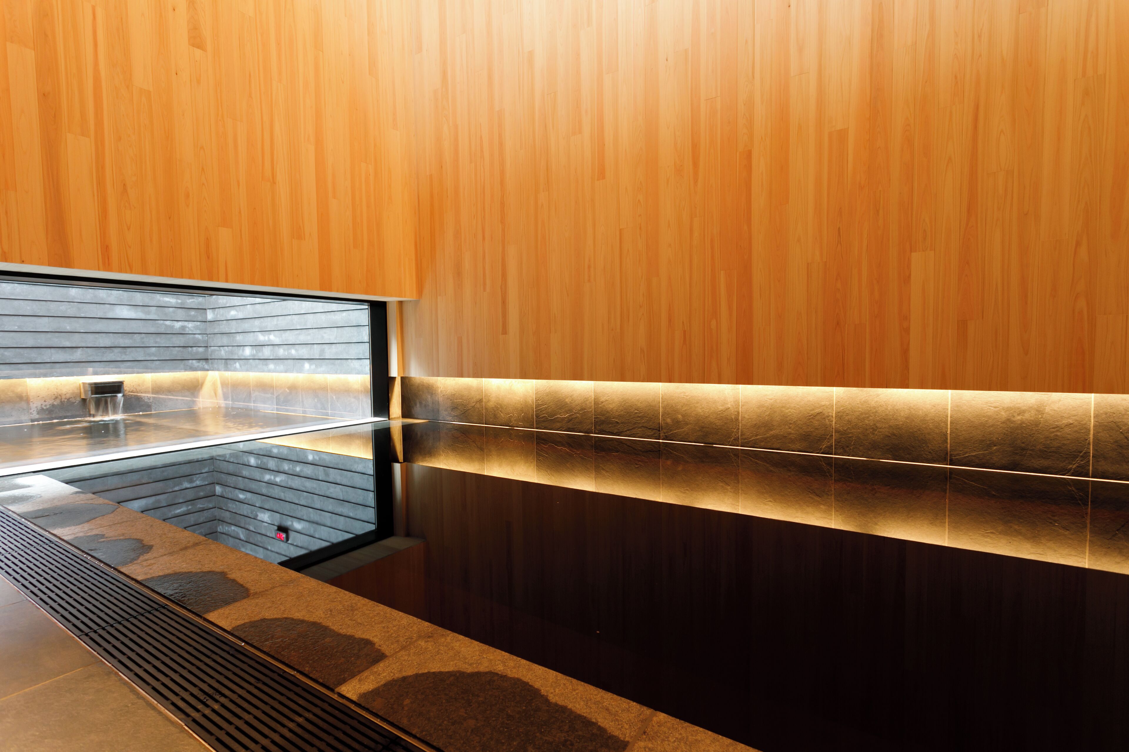 Un baño moderno con pared de madera, separador de vidrio y suelo con calefacción.