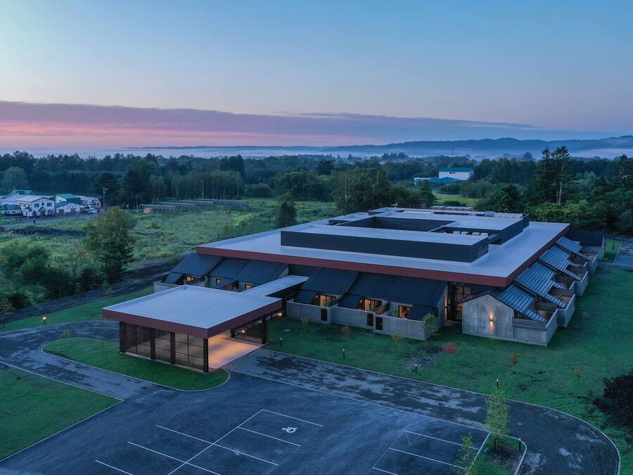 A modern building with a flat roof, large windows, and a covered entrance area.
