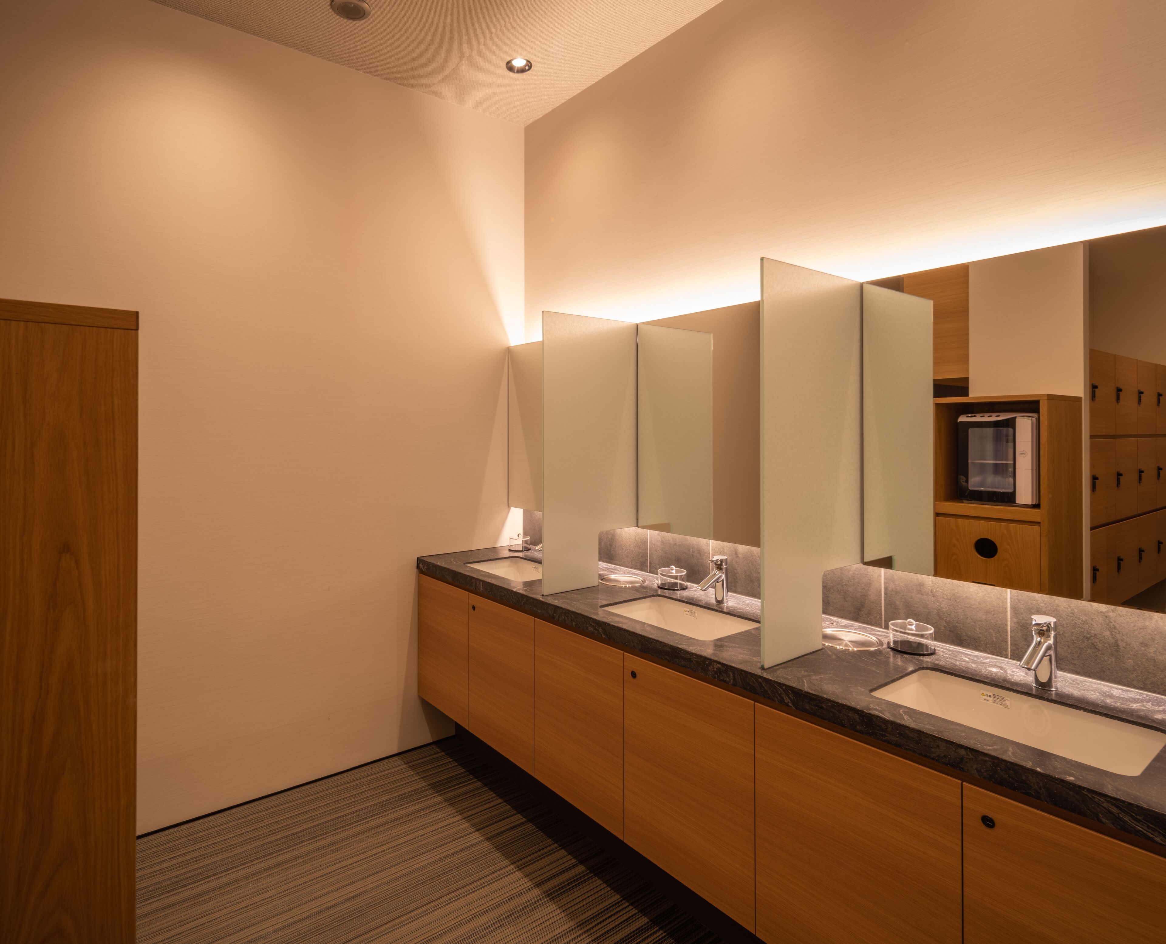 Un baño moderno con dos lavamanos, un espejo grande y armarios de madera.