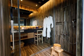 Une salle de bain moderne avec un lambris en bois, une cabine de douche en verre et un tabouret en bois.