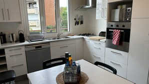 A modern kitchen with white cabinets, a gas stove, a microwave, and a dishwasher. - Pleasant townhouse between Paris and Disneyland park (Vaires-sur-Marne)