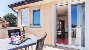 Un balcon avec une table dressée pour deux personnes, une bouteille de vin et un plateau avec des verres et une lanterne rose.