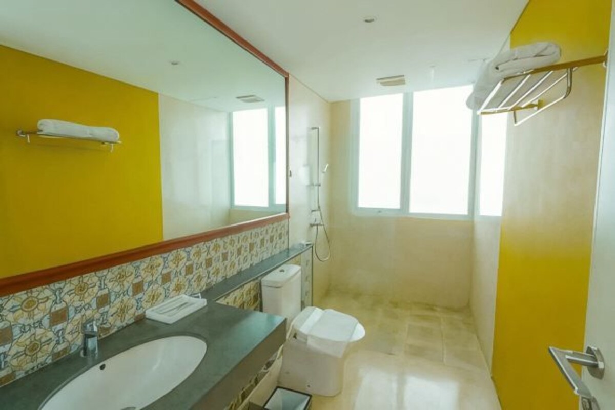 Une salle de bain avec un lavabo, un miroir, une douche et une fenêtre.
