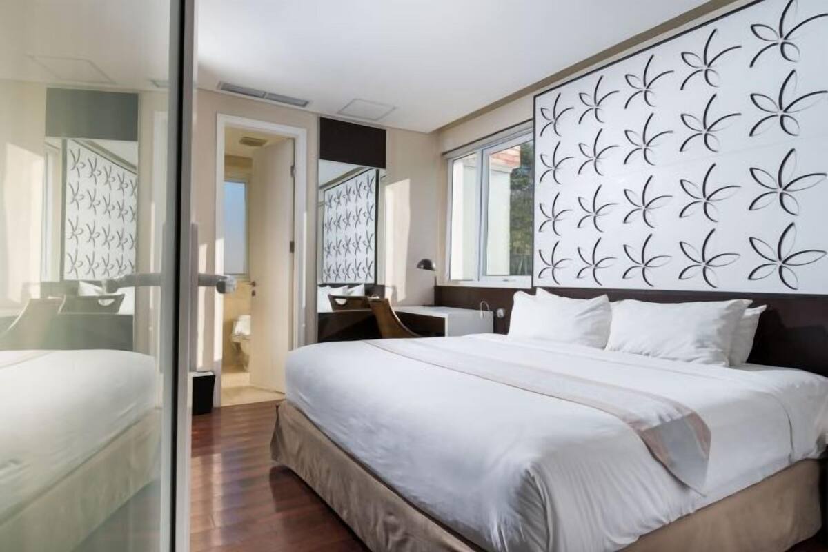 A bedroom with a bed, a desk, and a large window.