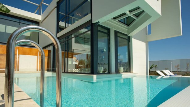 Ein moderner Poolbereich mit klarem, blauem Wasser, Glaswänden und einer Metallleiter.