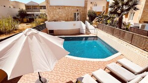 Ein Dachpool mit Liegestühlen und einer überdachten Sitzgruppe.