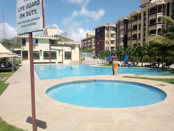 A swimming pool area with a sign indicating a life guard on duty.