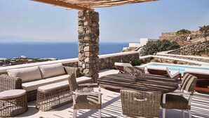 A terrace with wicker furniture, a stone pillar, and a view of the sea. - Villa Licata - 2BD, Luxury villa, near beach Elia (Elia)