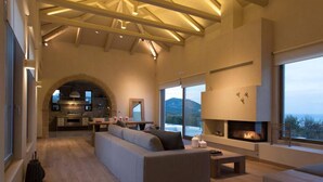 Un'ampia zona giorno con camino, divano e cucina sullo sfondo.