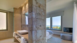 Un bagno moderno con una parete in pietra decorativa, una grande finestra e un televisore nella stanza.