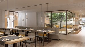 Un cafè modern amb taules de fusta, seients amb coixinets i llums penjants.