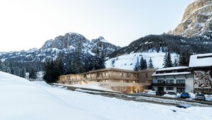 Un hotel amb disseny modern, ubicat en una zona muntanyosa nevada amb vista als cims circumdants.