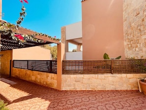 A covered outdoor area with a pergola, stone walls, and a tiled floor.