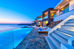 Un bâtiment moderne doté d’une piscine, d’un espace extérieur aménagé et offrant une vue sur la mer.