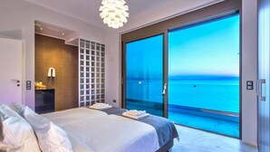 A modern bedroom with a large bed, a walk-in closet, and a balcony with a sea view. - Villa Blue Lagoon -Unifying your luxury senses -SEAFRONT (Chania Akrotiri)